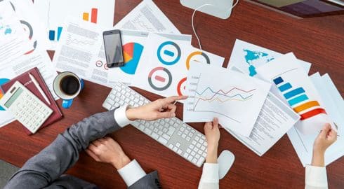 Manos analizando gráficos financieros como parte de un proceso de reestructuración empresarial con Resultae